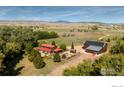 Sprawling property featuring the home, outbuildings, mature trees and landscaping against the distant mountains at 15789 N 83Rd St, Longmont, CO 80503
