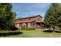 Two-story home boasts brick accents, a red roof, mature trees, and well-manicured lawn at 15789 N 83Rd St, Longmont, CO 80503