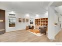 Bright living room with hardwood floors, built-in bookshelves, modern art, and neutral decor at 16060 Fairway Dr, Commerce City, CO 80022