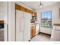 Bright kitchen featuring white appliances, wood cabinets, and a large window overlooking the outside at 17580 E Temple Dr, Aurora, CO 80015