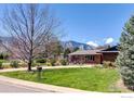 Classic brick home with mature trees, a well maintained lawn, and mountain views in the background at 205 Lipan Way, Boulder, CO 80303
