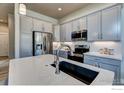 Contemporary kitchen boasts gray cabinets, stainless steel appliances, and a spacious quartz countertop at 208 High Point Dr, Longmont, CO 80504