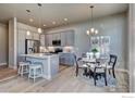 Bright kitchen featuring an island, gray cabinets, stainless steel appliances, and a dining area at 208 High Point Dr, Longmont, CO 80504