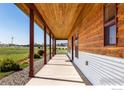 Long, covered side porch featuring wood beams and siding, accented by greenery and gravel at 2139 S County Road 15, Berthoud, CO 80513