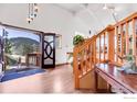 Inviting entryway with hardwood floors, wooden staircase, and an open door showcasing the mountain view at 2345 Point Of Pines Dr, Boulder, CO 80302