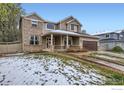 Charming two-story home featuring a covered porch, brick accents, and a well-maintained front yard with snow at 2834 Blue Jay Way, Lafayette, CO 80026