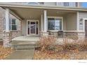 Inviting front porch with seating, brick pillars, and a storm door, creating a welcoming entrance at 2834 Blue Jay Way, Lafayette, CO 80026
