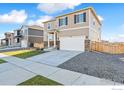 Inviting two-story home features neutral siding, stone accents, lush lawn, and a spacious two-car garage at 4732 Windmill Dr, Brighton, CO 80601
