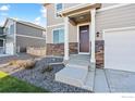 Close-up of a charming home entrance featuring a stone facade, covered porch, and manicured landscaping at 4732 Windmill Dr, Brighton, CO 80601