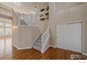 Bright foyer featuring hardwood floors, a staircase, and decorative wall art at 6317 Ruby Hill Dr, Frederick, CO 80516