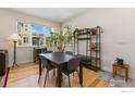 Cozy dining area with hardwood floors, a modern table, and natural light from large windows at 671 Robert St, Longmont, CO 80503