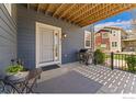 Inviting front porch with a sitting area, grill, and a view of the well-maintained yard at 671 Robert St, Longmont, CO 80503