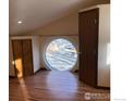 Bright bedroom with beautiful hardwood floors and a large, round window offering a unique view at 843 Sumner St, Longmont, CO 80501