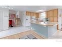 Bright kitchen with wood cabinets, a large island, and adjacent staircase at 10538 Quivas St, Northglenn, CO 80234