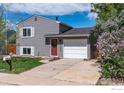 Inviting two-story home with gray siding, red front door, and an attached garage and driveway at 10683 Newcombe Way, Broomfield, CO 80021