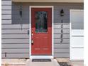 Close-up of a red front door with decorative glass and the house number displayed above at 10683 Newcombe Way, Broomfield, CO 80021