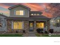 Inviting two-story home featuring a stone facade, cozy front porch, and a beautiful sunset backdrop at 11738 Zenobia Loop, Westminster, CO 80031