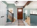 Warm entryway with wood door, staircase, and tiled flooring, featuring a stylish rug at 14117 W 58Th Pl, Arvada, CO 80004
