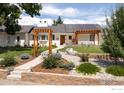 Charming home exterior with pergola, solar panels, manicured lawn, and inviting landscaping at 14117 W 58Th Pl, Arvada, CO 80004
