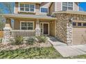 Close up of the front entrance featuring a stone facade, covered porch, and well-maintained landscaping at 1602 Prairie Song Pl, Longmont, CO 80504