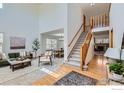 Open-concept living room with hardwood floors, a staircase and an adjacent dining area at 1602 Prairie Song Pl, Longmont, CO 80504