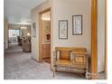 Hallway with neutral carpet, a wooden bench, and views into the bathroom and living areas at 1609 16Th Pl, Longmont, CO 80501