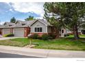 View of attractive home with brick accents, a tidy lawn, and mature trees shading the property at 1609 16Th Pl, Longmont, CO 80501
