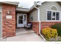 Inviting entrance with brick details, a cozy chair, and a welcoming front door with wreath at 1609 16Th Pl, Longmont, CO 80501