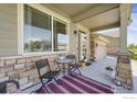 Inviting front porch with stylish seating, a decorative rug, and stone pillar accents at 17052 Lipan St, Broomfield, CO 80023