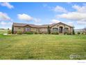 Tan home with a large lawn, manicured shrubs and mature trees in a desirable neighborhood at 1868 Preserve Dr, Berthoud, CO 80513