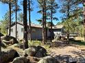 Mountain home featuring mature trees, large boulders, and a cozy deck, seamlessly blending nature at 191 Alder Ln, Boulder, CO 80304