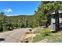Scenic street view of a mountain home, surrounded by lush trees and distant mountain peaks at 191 Alder Ln, Boulder, CO 80304