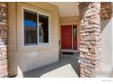 Inviting front entrance with a bright red door, stone columns, and a 'Welcome Home' mat at 1930 N Shore Dr, Longmont, CO 80503