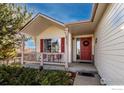 Cozy front porch featuring a red door, a wreath, and red shutters at 2344 Flagstaff Dr, Longmont, CO 80504