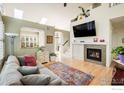 Bright living room with a fireplace, hardwood floors, and a cozy couch with colorful accents at 2758 Meadow Mountain Trl, Lafayette, CO 80026
