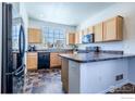 Kitchen with wooden cabinets, black appliances, and a large window at 5659 Viewpoint Ave, Firestone, CO 80504