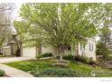 Lovely two-story home with a well-manicured lawn, mature tree, and inviting bench at 6646 Bean Mountain Ln, Boulder, CO 80301