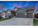 Charming home with stone accents, a well-manicured lawn, and a three-car garage at dusk at 719 Wagon Bend Rd, Berthoud, CO 80513