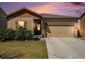 Tan home with a 2 car garage, landscaped yard, and concrete driveway at dusk at 7225 Shavano Ave, Frederick, CO 80504