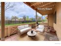 Virtually staged covered patio features outdoor furniture and brick flooring, with wood fence and backyard views at 1100 Bacchus Dr # A, Lafayette, CO 80026