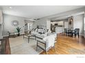 Bright, open-concept living room with hardwood floors, neutral walls, and modern furniture, flowing into the kitchen at 1230 Tyler Pl, Erie, CO 80516
