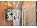 Warm entryway featuring wood floors, stylish lighting, and a decorative wreath on the front door at 14394 W 88Th Dr # C, Arvada, CO 80005