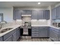 Modern kitchen featuring gray cabinetry, stainless steel appliances, and stylish backsplash at 1978 E 102Nd Cir, Thornton, CO 80229