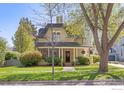Beautiful home with mature trees, a well-kept lawn, and an inviting front porch decorated with flowers at 318 Pratt St, Longmont, CO 80501