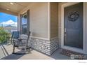 Inviting front porch with rocking chairs and a decorative wreath on the front door at 3295 Heron Lakes Pkwy, Berthoud, CO 80513