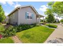Side view of cozy home with green lawn and shrubs, showcasing a light-colored exterior, light-trim, and a pop of color at 4672 Clear Creek Dr, Longmont, CO 80504