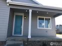 Covered front porch with light fixtures, a blue front door, and a view of the front lawn at 4672 Clear Creek Dr, Longmont, CO 80504
