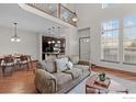 Spacious living room with hardwood floors, large windows, and an open floor plan connected to the kitchen at 4822 Raven Run, Broomfield, CO 80023