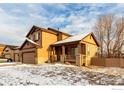 Exterior side view of home with front porch, showcasing snow-covered yard and fence at 548 Mathews Cir, Erie, CO 80516