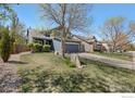 Exterior view of a well-manicured lawn with a mature tree in front of the blue two-story home at 5822 Shenandoah Ave, Firestone, CO 80504